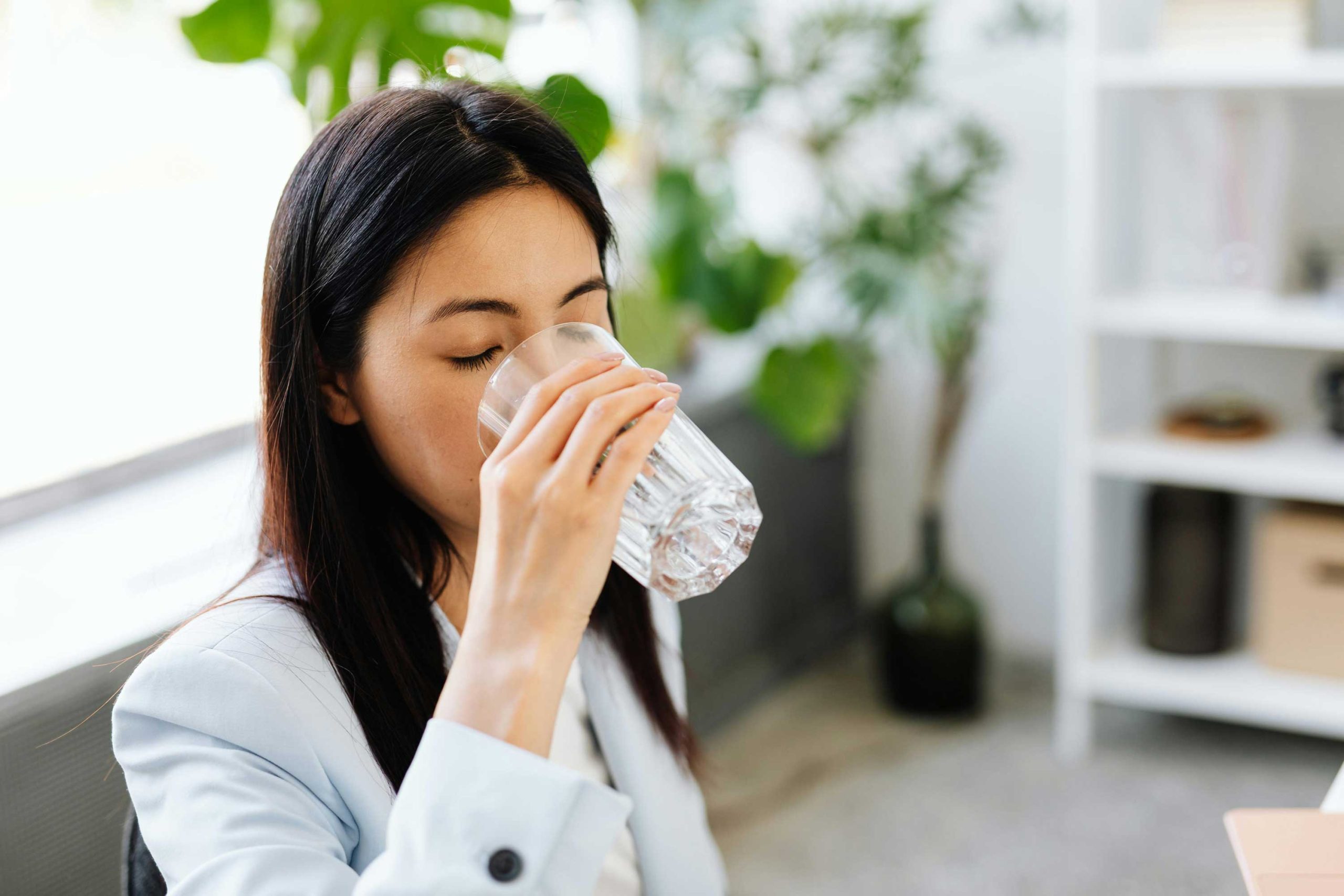 Brunette professional woman drinking from a glass of water in an office